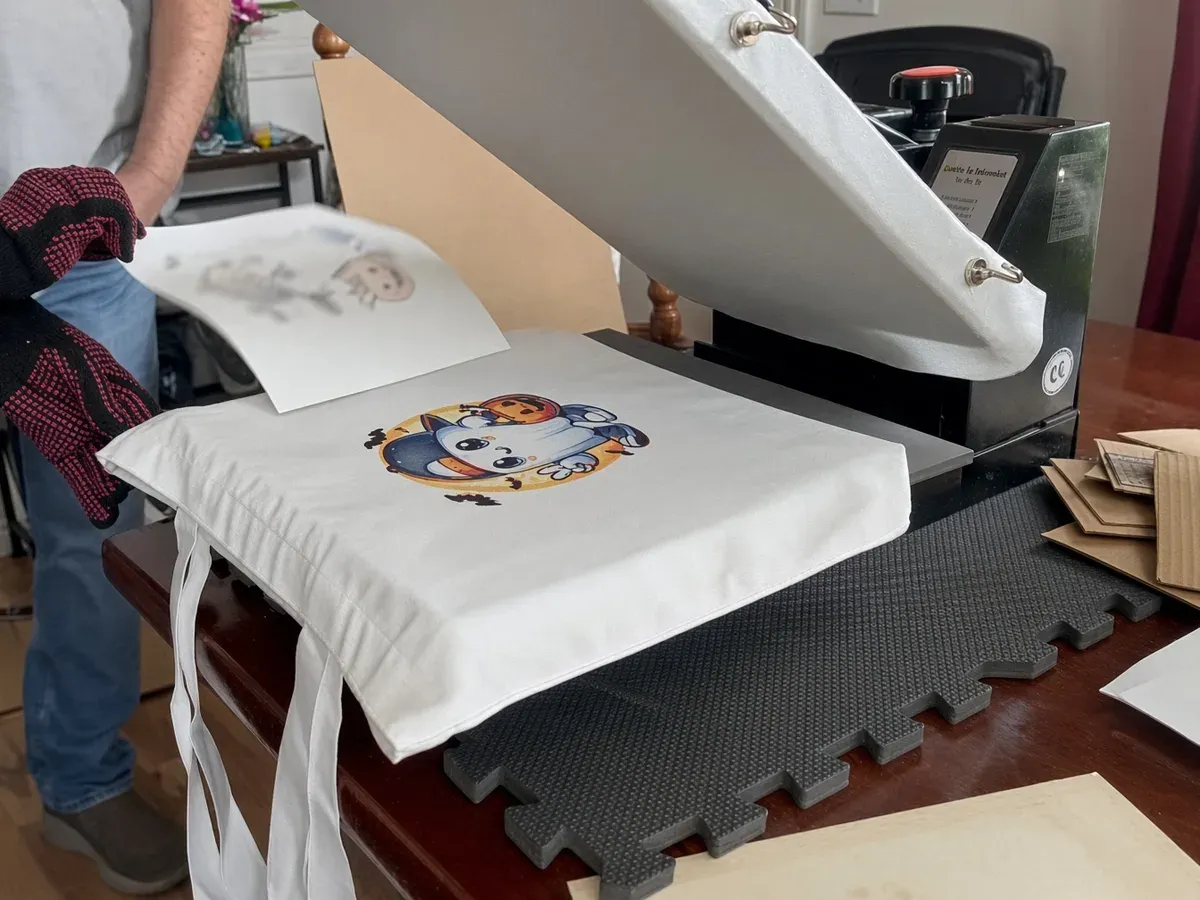 A printed tote bag being lifted off a heat press after the transfer is applied