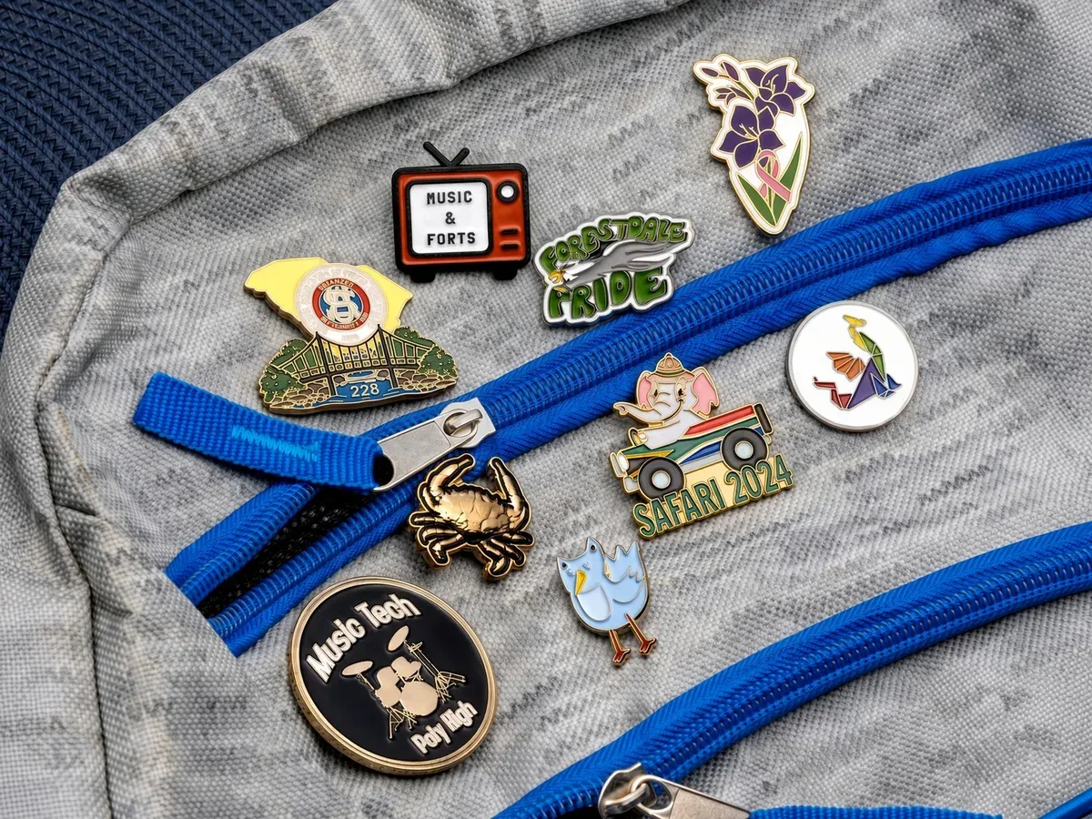 A collection of hard enamel pins attached to a nylon backpack