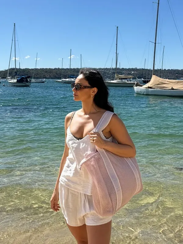 Pink mesh beach bag held in shallow water