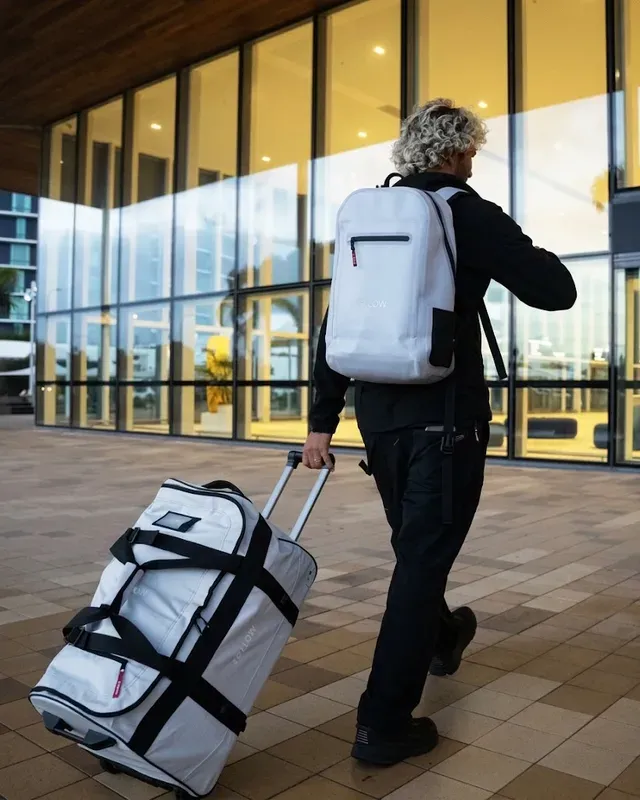 Rolling travel duffle with a matching backpack, carried past a glass-fronted building