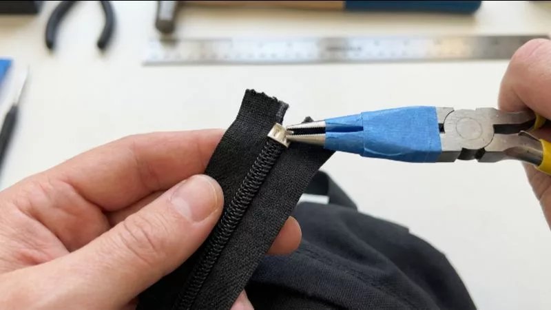 テープを巻いたラジオペンチを使って金属製のファスナー上部ストッパーを取り外す