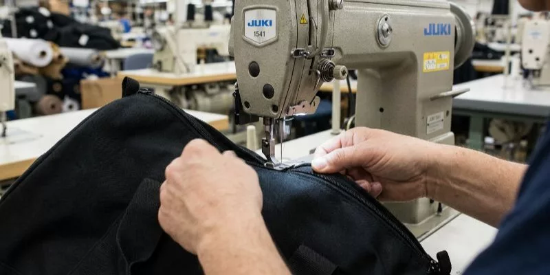 5. Worker sewing a duffle bag zipper on a Juki 1541 sewing machine.