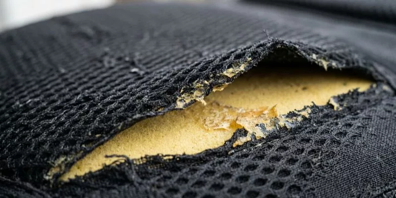 Macro close-up of spacer mesh wrinkling and delaminating from EVA foam on a backpack panel