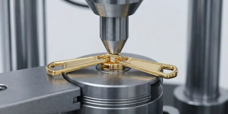 Test di abrasione su una cerniera lampo in una macchina per componenti industriali.