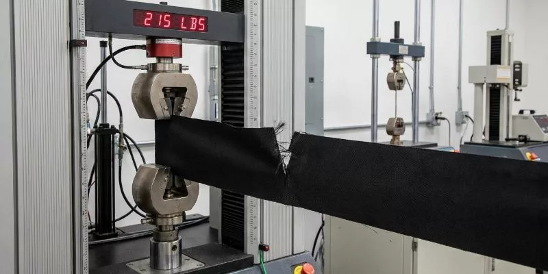 Fabric tensile testing machine snapping a piece of 500D polyester at 215 pounds of force.