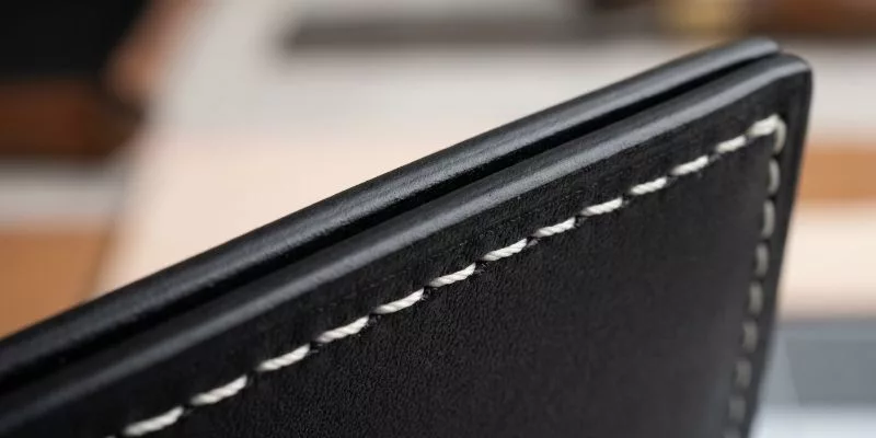 Gros plan macro d'une peinture noire parfaitement lisse sur des panneaux de cuir de luxe cousus.