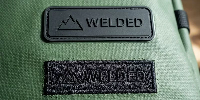 Welded waterproof rubber patch logo compared to a stitched embroidery logo