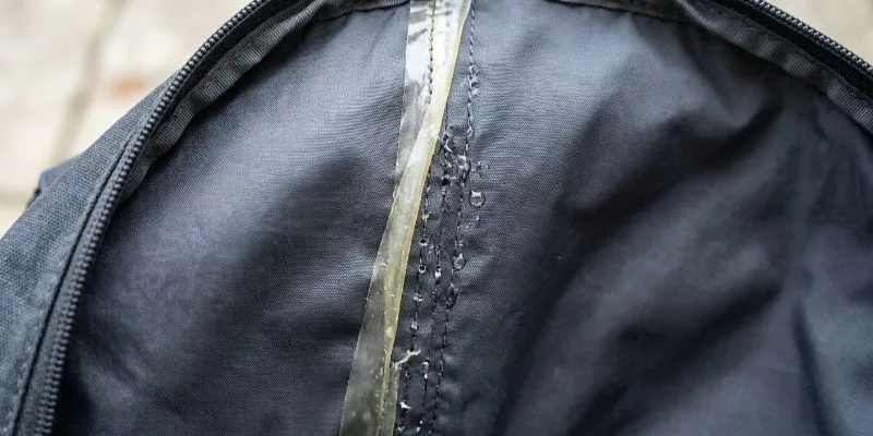 Clear waterproof seam tape peeling off inside a stitched nylon backpack